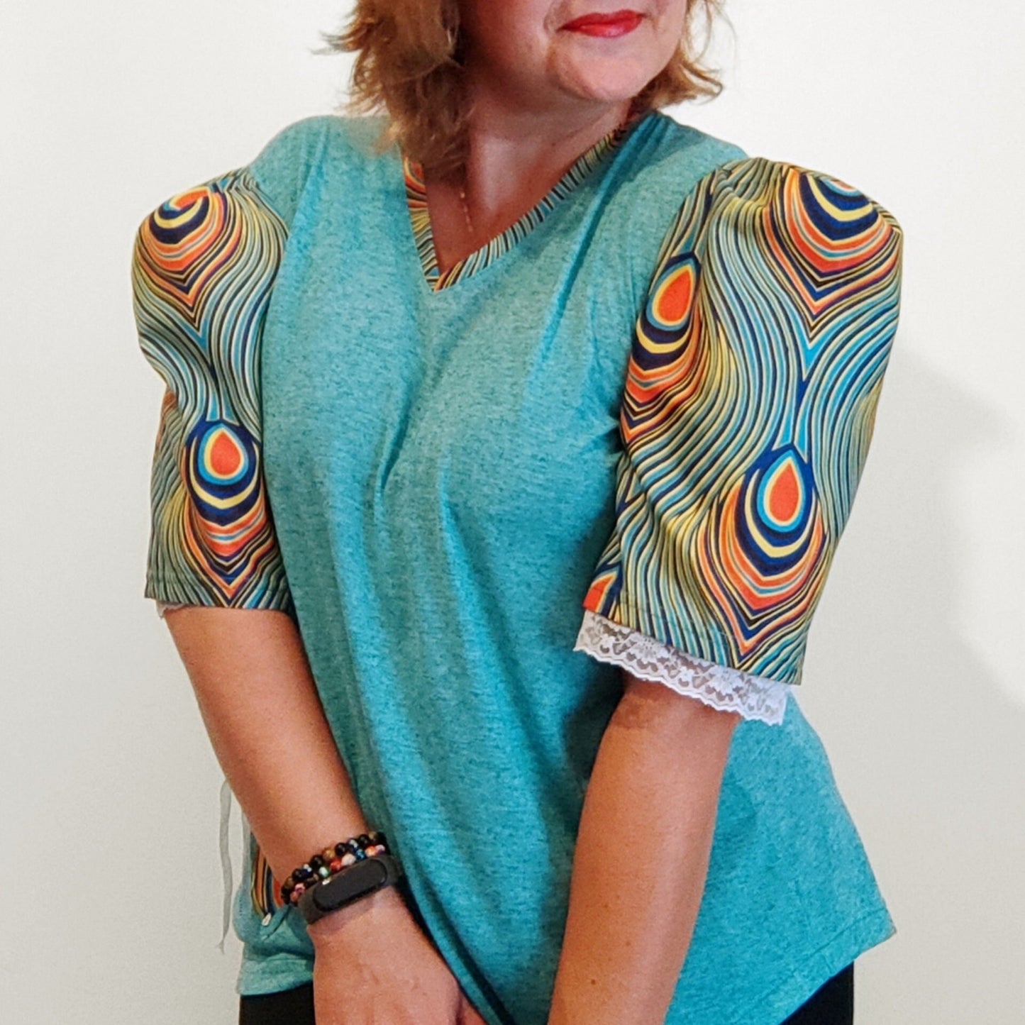 T-shirt para senhora em algodão azul com mangas em balão feitas em capulana com desenho de penas de pavão, disponível em vários tamanhos