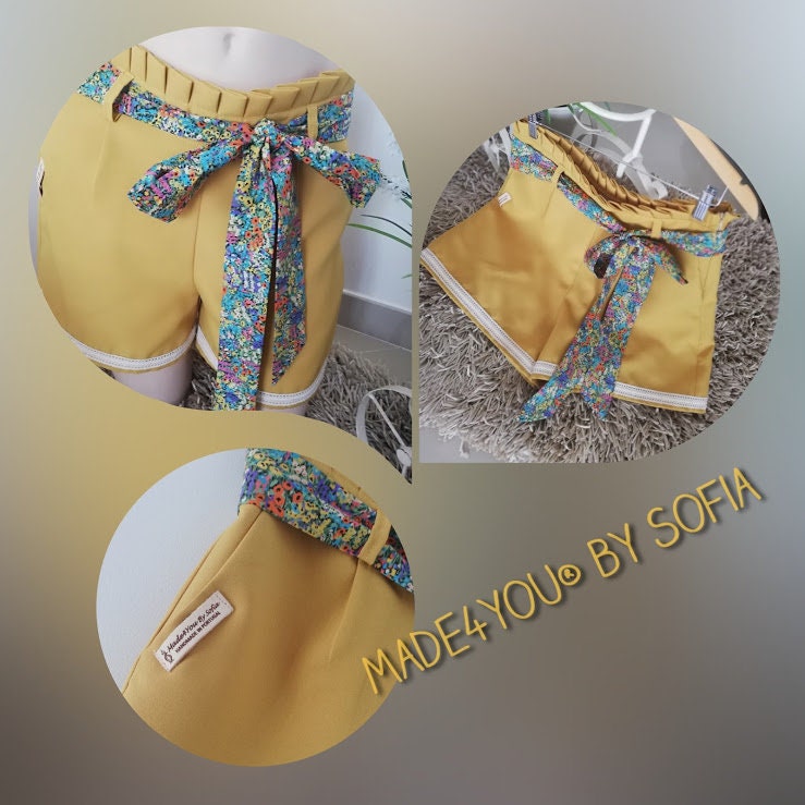 Calção artesanal de mulher em amarelo mostarda com pormenores de renda, cinto floral e efeito pregueado na cintura