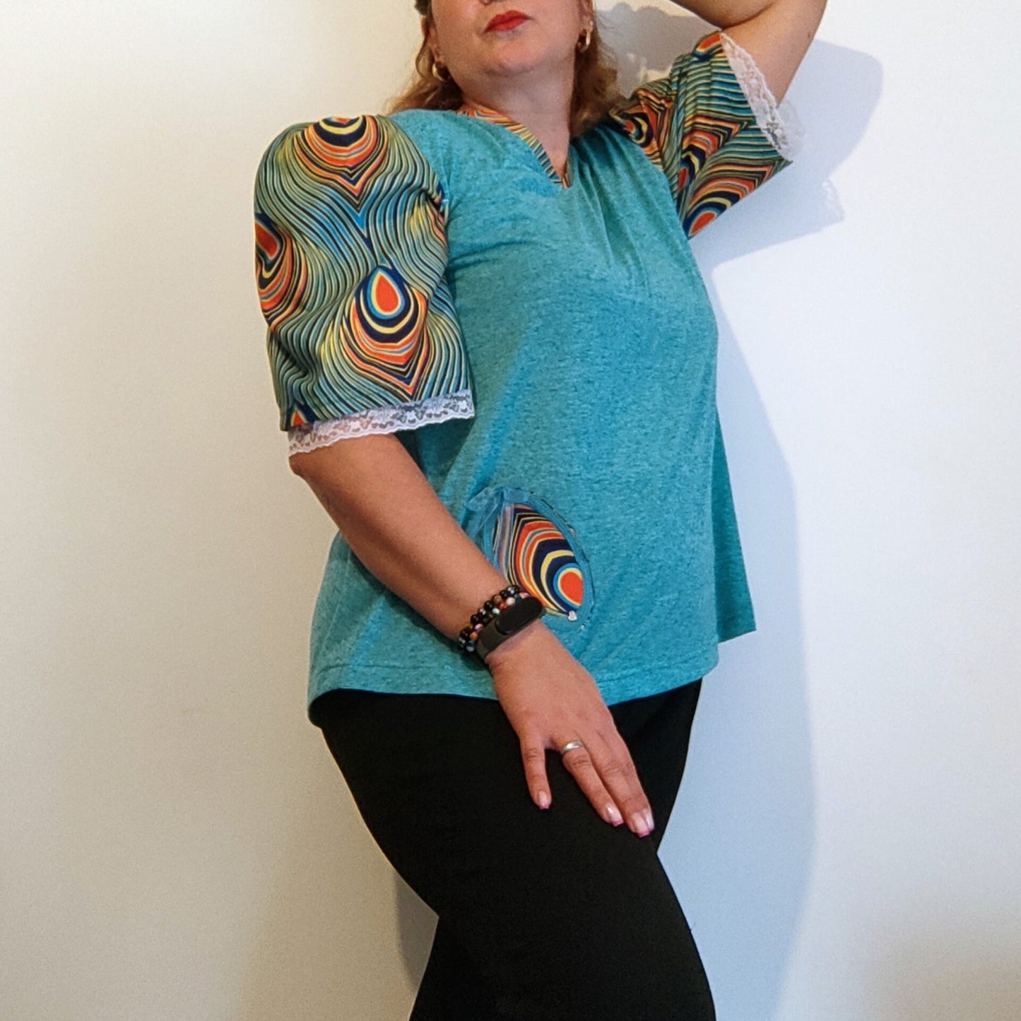 T-shirt para senhora em algodão azul com mangas em balão feitas em capulana com desenho de penas de pavão, disponível em vários tamanhos