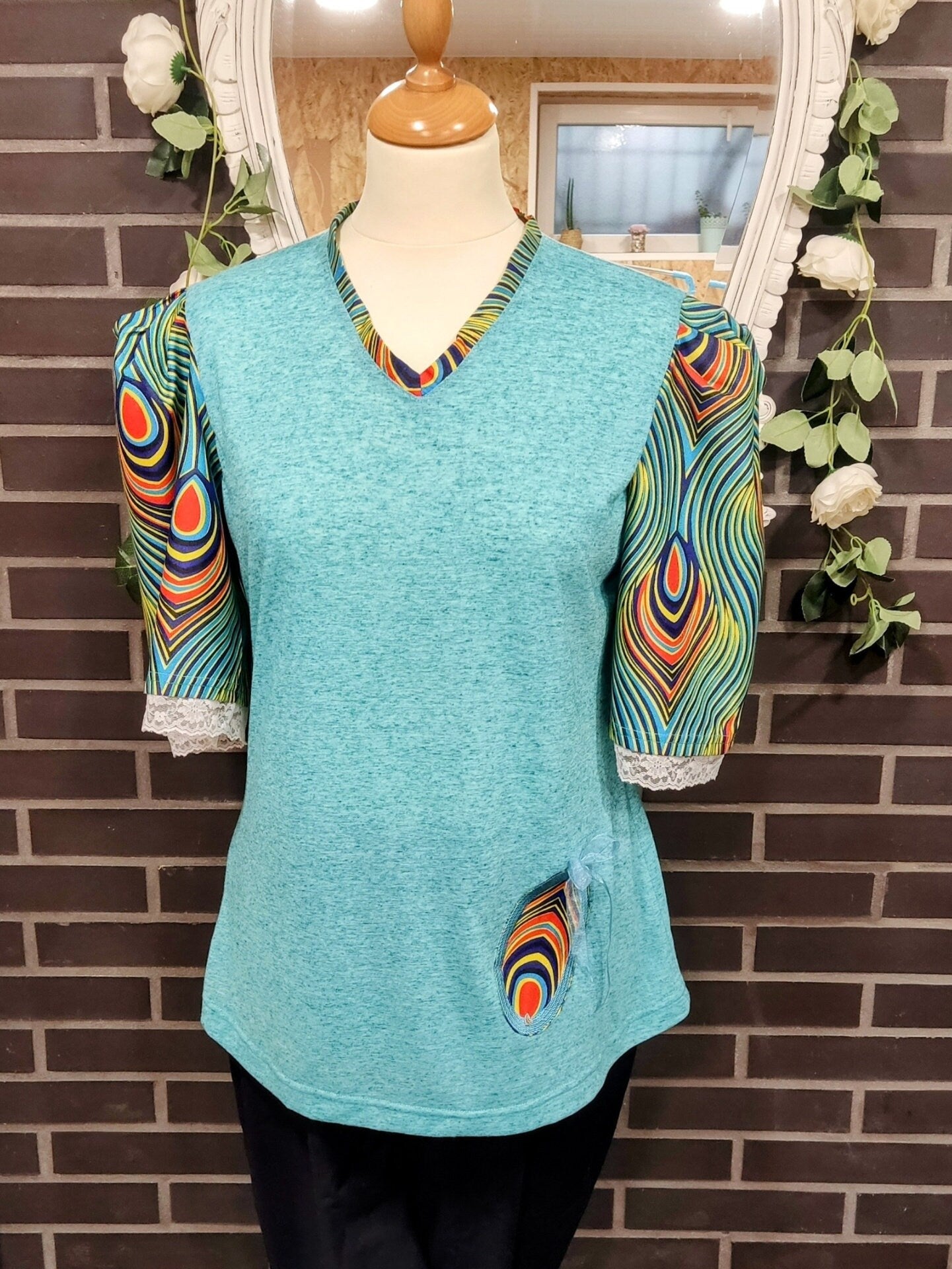 T-shirt para senhora em algodão azul com mangas em balão feitas em capulana com desenho de penas de pavão, disponível em vários tamanhos