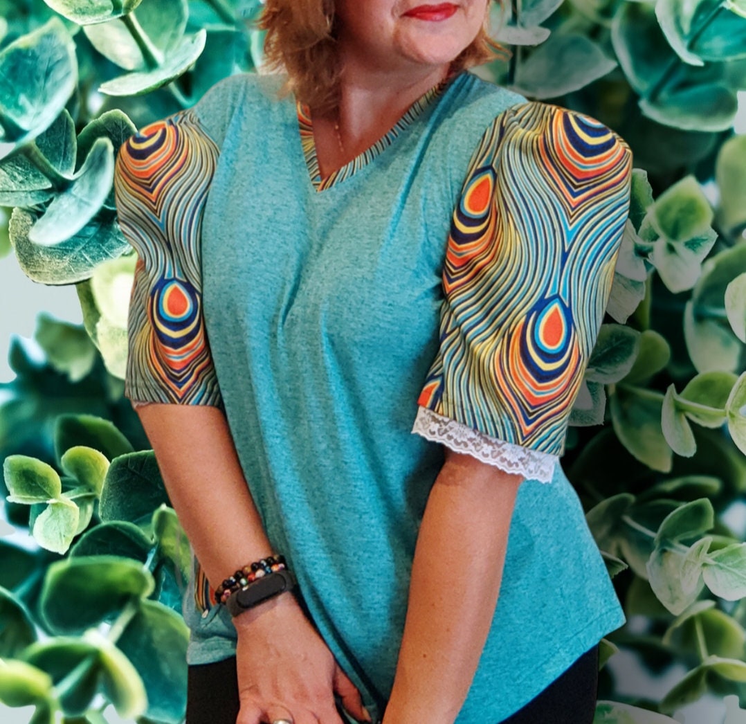 T-shirt para senhora em algodão azul com mangas em balão feitas em capulana com desenho de penas de pavão, disponível em vários tamanhos